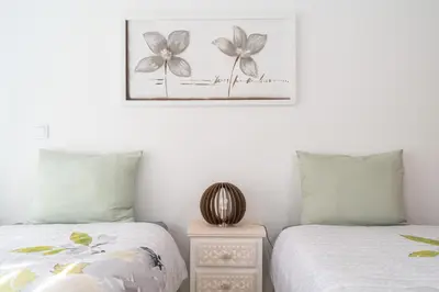 a bedroom with two beds and a picture on the wall at Casa Leonardo in Arco da Calheta