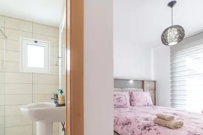 a white bedroom with a pink bed and a sink at Casa Leonardo in Arco da Calheta