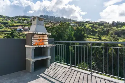 a patio with a fireplace on a balcony at Casa Leonardo in Arco da Calheta
