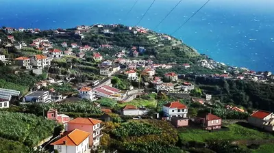 a village on a hill with houses and the ocean at Lindo Apartamento Villa in Ponta do Sol