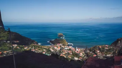 a town on a hill next to the ocean at Hotel Vila Bela in Porto da Cruz