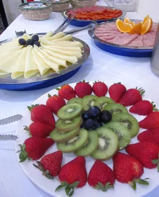 a table topped with plates of strawberries and fruit at Hotel Vila Bela in Porto da Cruz