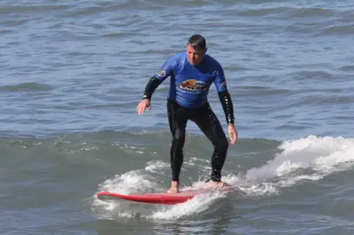 a man riding a wave on a surfboard in the ocean at Hotel Vila Bela in Porto da Cruz