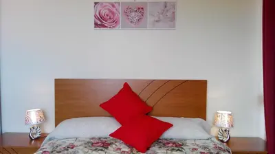 a bed with red pillows on top of it at Appartamento Villa in Ponta do Sol