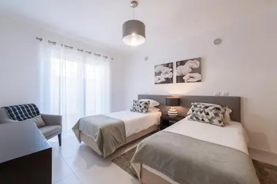 a bedroom with two beds and a chair at Porto de Mós 85 by Destination Algarve in Lagos