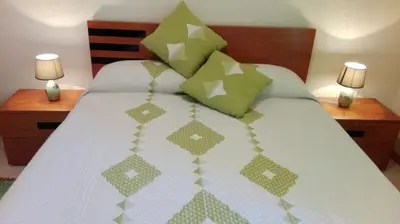 a bed with green and white sheets and pillows at Apartamento Villa in Ponta do Sol