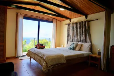 a bedroom with a bed with a large window at Ocean View Cottage in Ponta do Pargo