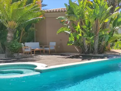 a pool with a table and chairs next to a house at Casa Canavial in Luz