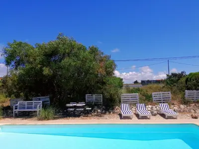 a group of chairs sitting next to a swimming pool at Endless Summer Surf House in Aljezur