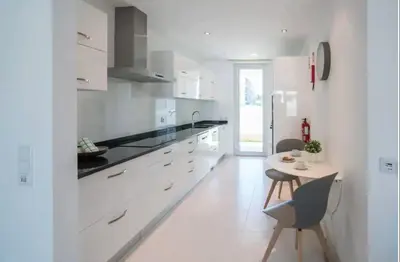 a kitchen with white cabinets and a table in it at ZENTUNI Ocean front in Lagos