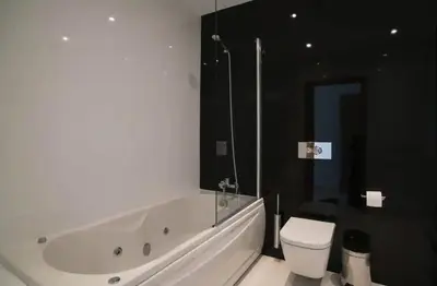 a white bathroom with a tub and a toilet at ZENTUNI Ocean front in Lagos