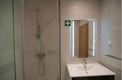 a bathroom with a sink and a shower with a mirror at ZENTUNI Ocean front in Lagos