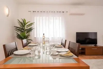 a dining room with a table with chairs and a television at Two Bedroom Apartment Vila Mos Lagos in Porto de Mós