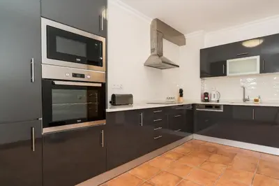 a kitchen with black cabinets and a tv on the wall at Two Bedroom Apartment Vila Mos Lagos in Porto de Mós