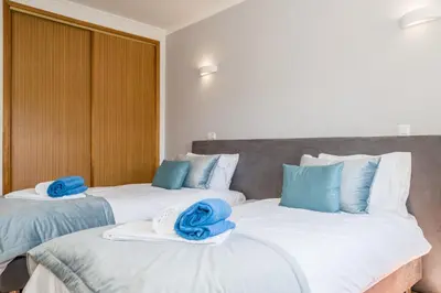 two beds in a room with blue towels on them at Two Bedroom Apartment Vila Mos Lagos in Porto de Mós