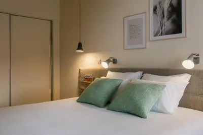 a bedroom with a white bed with two green pillows at Three House Hotel in Funchal