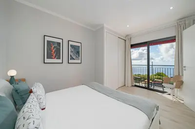 a white bedroom with a bed and a balcony at Vilas Felicidade Rocha by An Island Apart in Ponta do Pargo