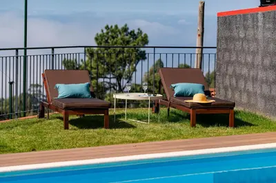 two chairs and a table next to a swimming pool at Vilas Felicidade Rocha by An Island Apart in Ponta do Pargo