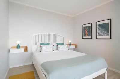 a white bedroom with a large white bed with blue pillows at Vilas Felicidade Rocha by An Island Apart in Ponta do Pargo
