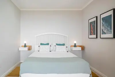 a white bedroom with a large bed and two lamps at Vilas Felicidade Rocha by An Island Apart in Ponta do Pargo