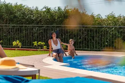 a woman and a boy sitting in a swimming pool at Vilas Felicidade Rocha by An Island Apart in Ponta do Pargo
