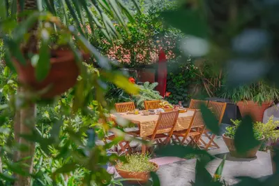 a table and chairs in a garden with potted plants at Madeira Surf Lodge in São Vicente