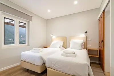 two beds in a white room with a window at Madeira Surf Lodge in São Vicente