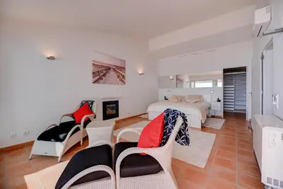 a bedroom with a bed and a couch and chairs at The Fantastic Beach House of Luz in Luz