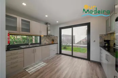 a kitchen with white cabinets and a large sliding glass door at OurMadeira - Casa Amaro Sunset in Calheta