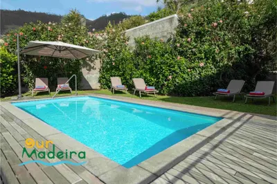 a swimming pool in a yard with chairs and an umbrella at OurMadeira - Casa Amaro Sunset in Calheta
