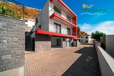 a building with a red balcony on a brick sidewalk at OurMadeira - Casa Amaro Sunset in Calheta