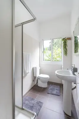 a white bathroom with a sink and a toilet at VillaHouse in São Vicente