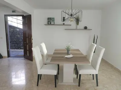 a dining room with a wooden table and white chairs at Casa Vanday in Funchal