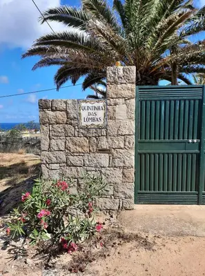 a sign on a stone wall next to a gate at Quintinha das Lombas S in Porto Santo