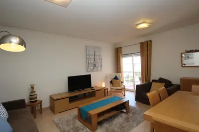 a living room with a couch and a tv at Brisa Mar para 4 com piscina e WiFi in Luz
