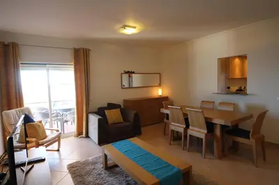 a living room with a table and a dining room at Brisa Mar para 4 com piscina e WiFi in Luz