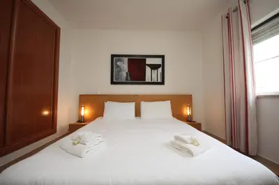 a bedroom with a white bed with two towels on it at Brisa Mar para 4 com piscina e WiFi in Luz
