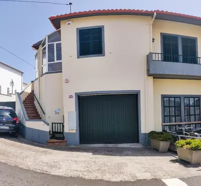 a white house with a green garage door at CASA Da CERCA ACHADA De GAULA in Santa Cruz
