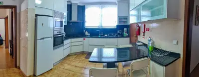 a large kitchen with a table and a refrigerator at CASA Da CERCA ACHADA De GAULA in Santa Cruz