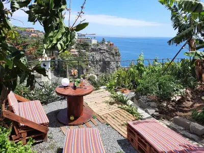 a patio with a table and chairs and the ocean at Encanto do Sol in Ponta do Sol