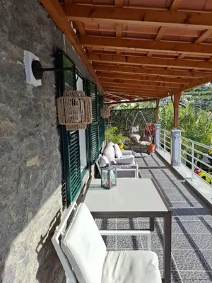 a patio with a table and chairs under a roof at Encanto do Sol in Ponta do Sol
