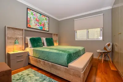 a bedroom with a large bed and a chair at Apartamento Boieiro Plaza in Caniço