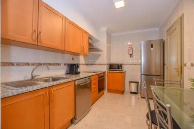 a kitchen with wooden cabinets and a stainless steel refrigerator at Apartamento Boieiro Plaza in Caniço