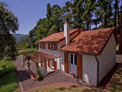 a small white house with a red roof at Quinta Das Colmeias Cottage in Santo da Serra