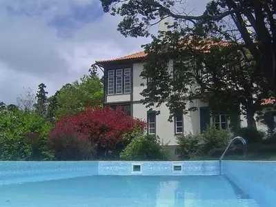 a house and a swimming pool in front of a house at Quinta Das Colmeias Cottage in Santo da Serra