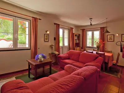 a living room with a red couch and a table at Quinta Das Colmeias Cottage in Santo da Serra