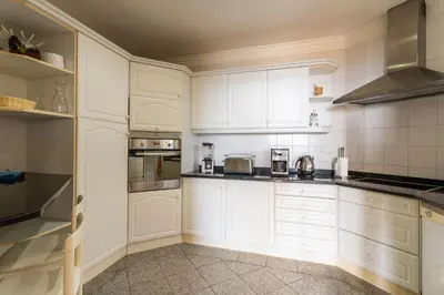 a white kitchen with white cabinets and appliances at FLH Vivenda Belo Horizonte with Sea View in Caniço
