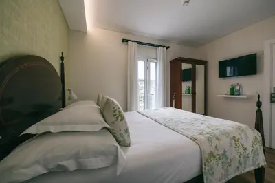 a bedroom with a bed with white sheets and a window at Quinta da Saraiva in Câmara de Lobos