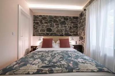 a bedroom with a bed and a stone wall at Quinta da Saraiva in Câmara de Lobos