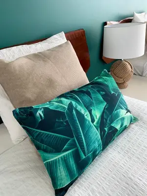a green pillow sitting on a bed next to a lamp at Villa Mar Garajau in Caniço